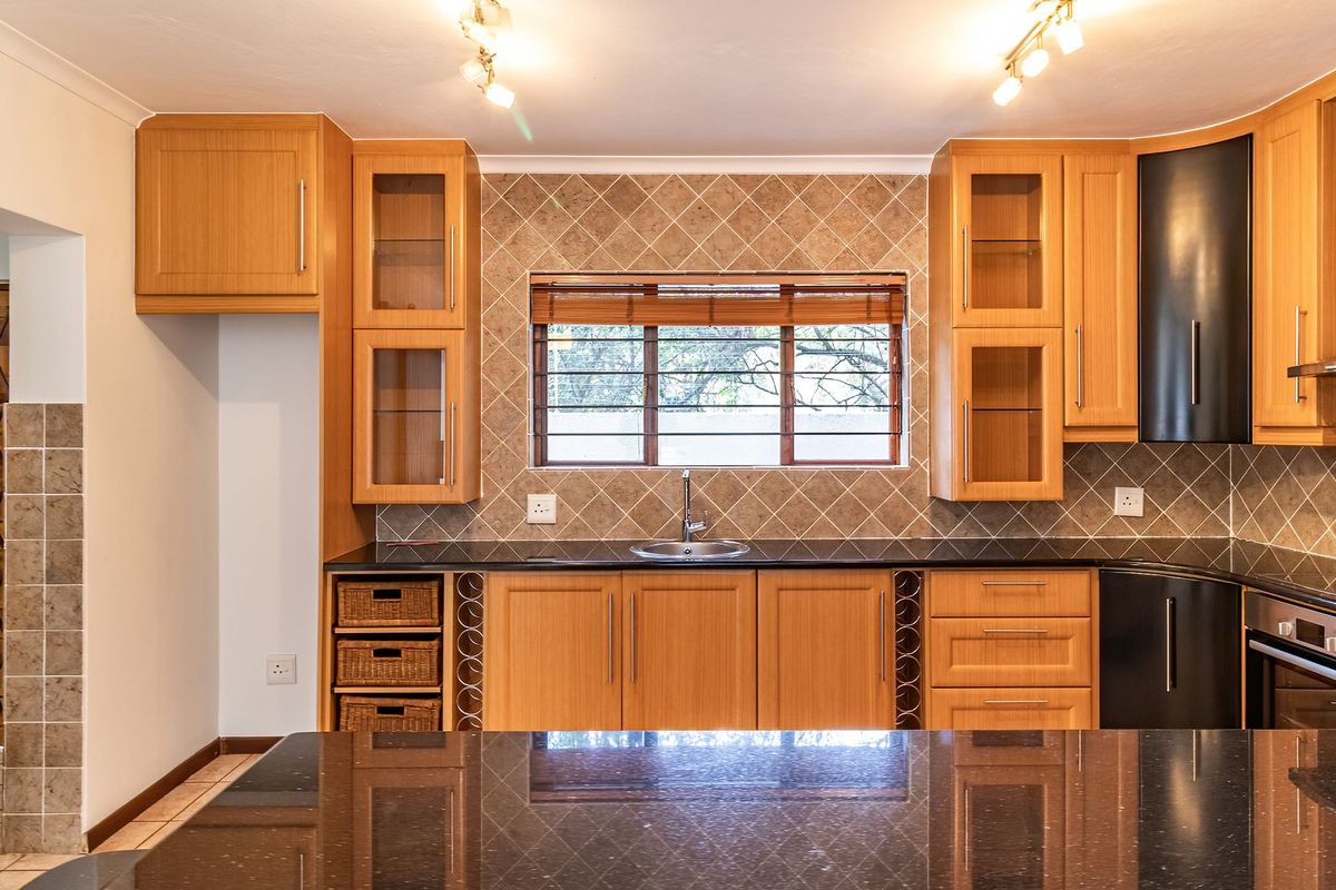 A well-maintained kitchen featuring wooden cabinetry, granite countertops, a tiled backsplash, and built-in appliances, offering a functional and clean workspace.