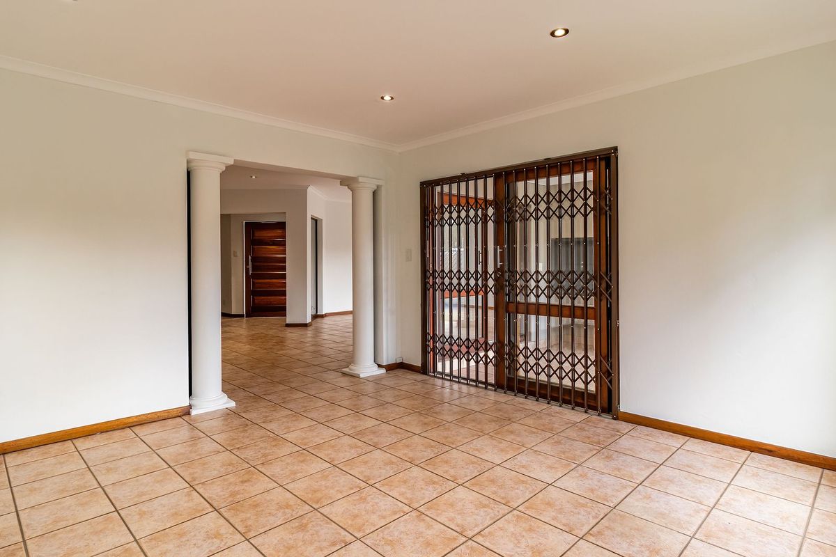 Spacious living area featuring ceramic floor tiles, decorative columns, and a secure sliding glass door leading to the exterior.