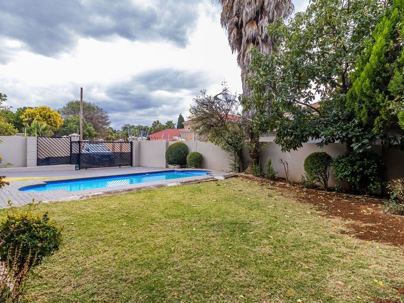 A private backyard featuring a swimming pool, paved surround, and perimeter walling, offering a functional outdoor space for recreation.