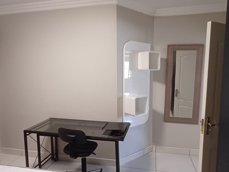A bedroom featuring tiled flooring, crown molding, and built-in wall shelving, providing a functional space with neutral wall finishes.