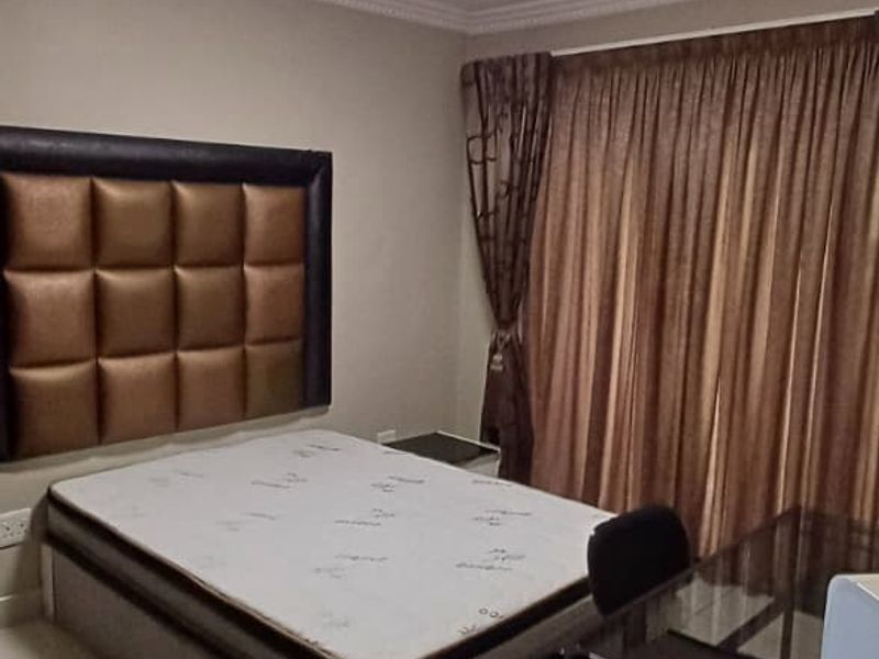 A functional bedroom featuring tiled flooring, ceiling cornice detailing, and a central flush mount light fixture.