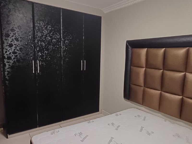 A bedroom featuring built-in cupboards with a decorative finish and crown molding detail.