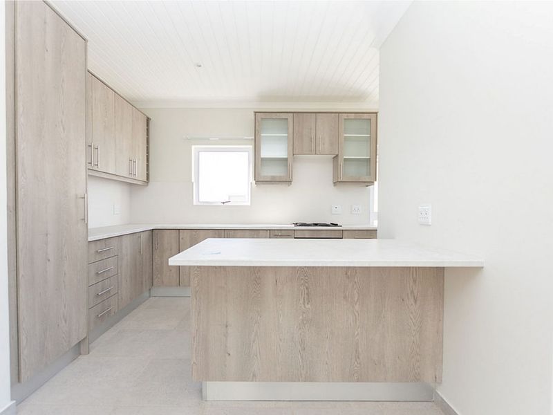Modern kitchen featuring light wood-grain cabinetry, stone-look countertops, a built-in hob, and a clean, neutral aesthetic with tiled flooring.