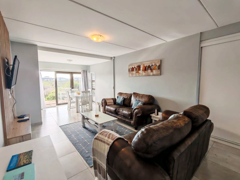 An open-plan living and dining area featuring tiled flooring, neutral walls, and a sliding glass door providing access to the outdoor space.