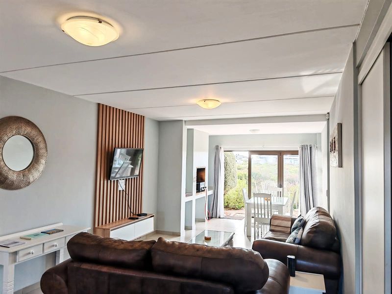 Open plan living area featuring a slatted timber wall accent, built-in fireplace, and sliding glass doors leading to an outdoor space.