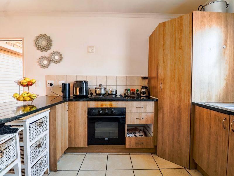 A functional kitchen featuring wood-finish cabinetry, granite countertops, a built-in oven, and tiled flooring, requiring minor repairs to cabinetry.
