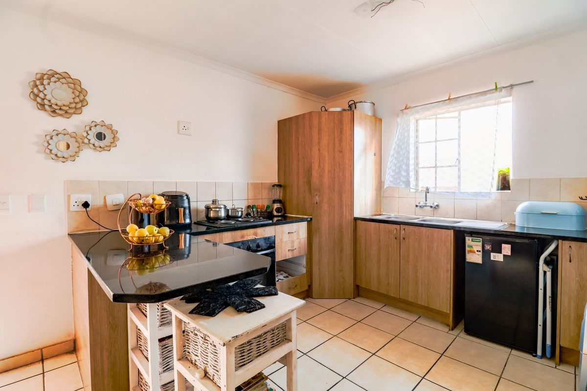 Functional kitchen featuring granite countertops, built-in oven, hob, and double sink with tiled flooring and backsplash.