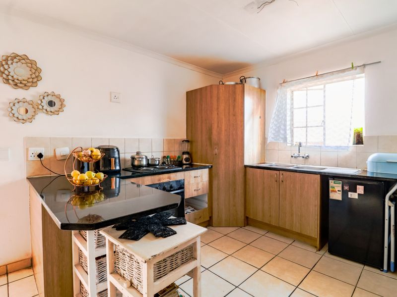 Functional kitchen featuring granite countertops, built-in oven, hob, and double sink with tiled flooring and backsplash.