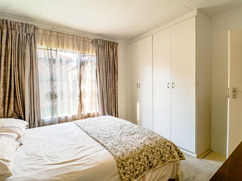 A well-lit bedroom featuring built-in cupboards and carpeted flooring, offering a functional and comfortable living space.