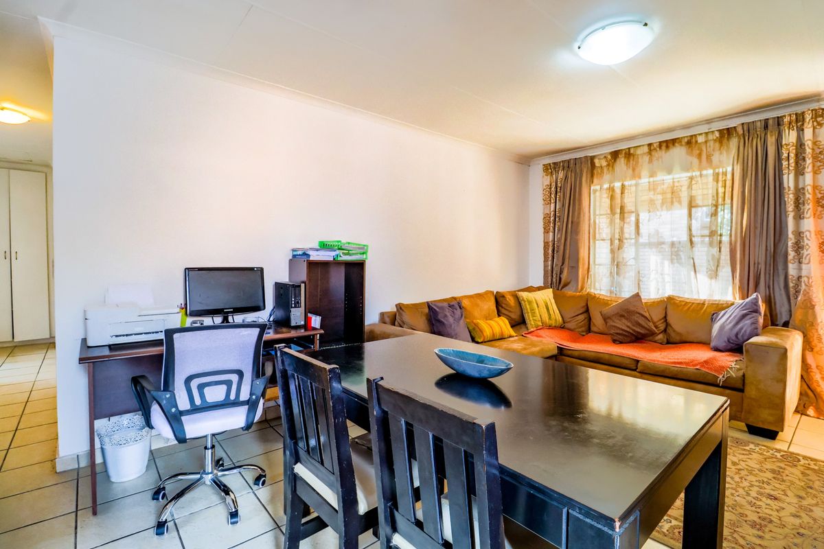 A functional living area featuring neutral tiled flooring and a central ceiling light fixture, providing a versatile space for relaxation and dining.