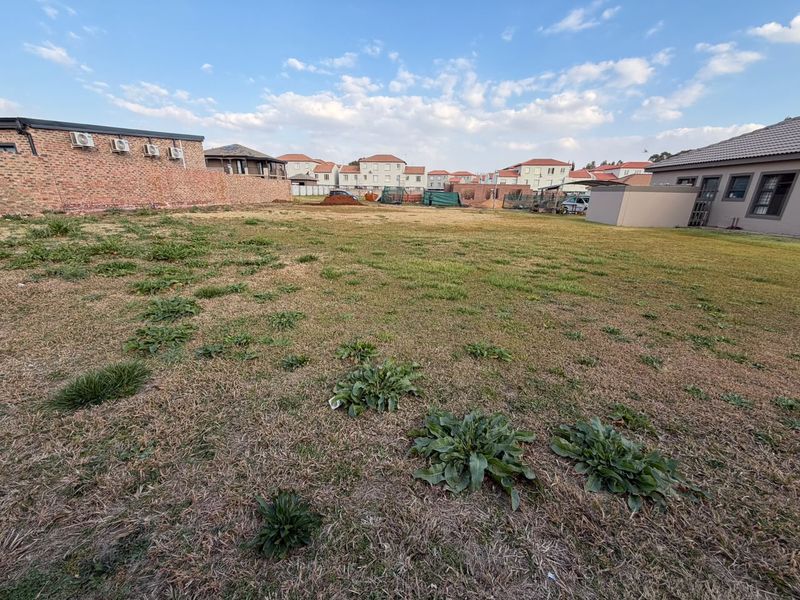 A view of a vacant residential plot featuring a grassed area and surrounding boundary walls in a developed estate setting.
