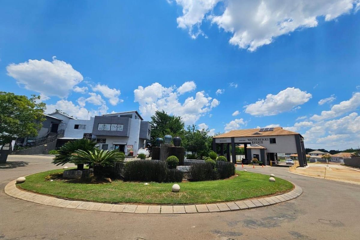 The entrance to Waterberry Estate featuring a landscaped roundabout with a central water fountain and a modern security gatehouse.