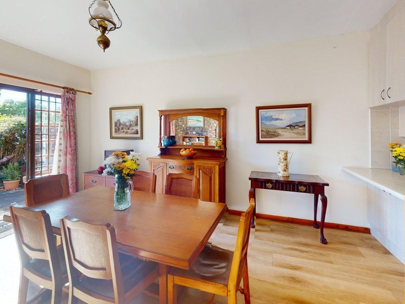Open-plan dining and kitchen area featuring laminate flooring, built-in cabinetry, and sliding glass doors providing direct access to the rear patio and garden.