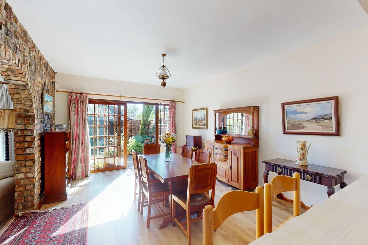 Spacious living and dining area featuring an exposed brick archway, light laminate flooring, and direct access to the rear garden through timber-framed glass doors.