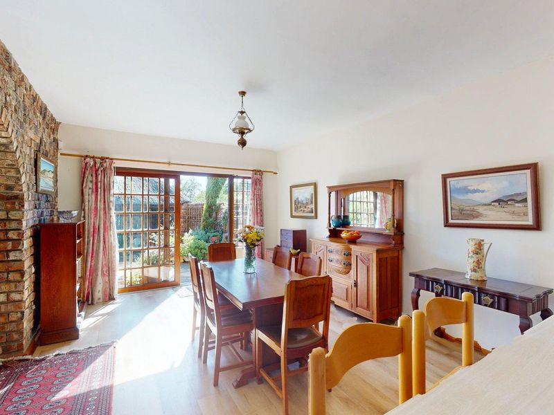 Spacious living and dining area featuring an exposed brick archway, light laminate flooring, and direct access to the rear garden through timber-framed glass doors.