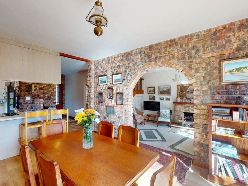 Open plan living and dining area featuring a distinctive brick archway, fireplace, and integrated kitchen space with wooden cabinetry.