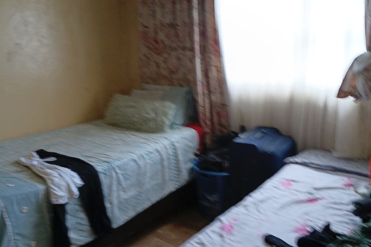 A bedroom featuring tiled flooring and window curtain rails, requiring cosmetic updates to the wall finishes.