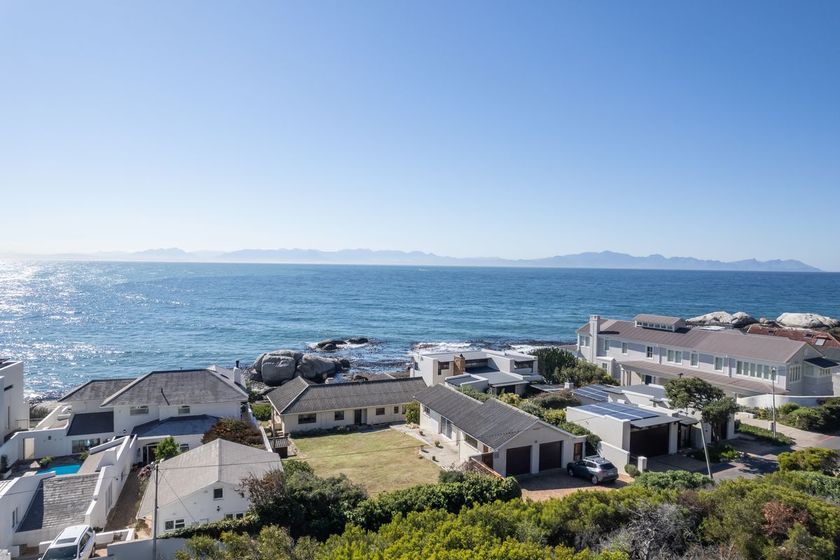 An elevated aerial view of a coastal residential neighborhood featuring homes with tiled roofs, solar panels, and direct ocean views.