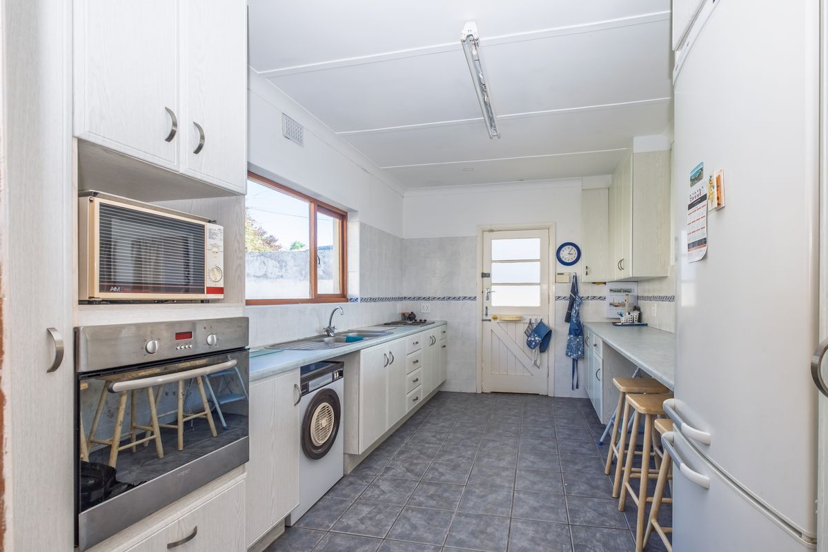 A functional kitchen featuring built-in oven and microwave, tiled flooring, ample cabinetry, and a classic stable door leading to the exterior.