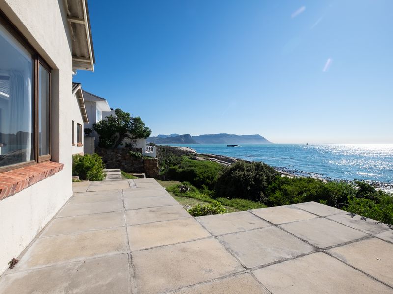 A rear paved patio area offering expansive ocean views, featuring a brick window sill and direct access to the coastal landscape.