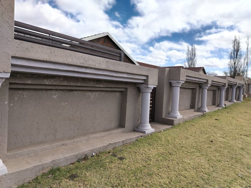 A view of the property's front boundary wall featuring decorative columns and integrated metal railing.