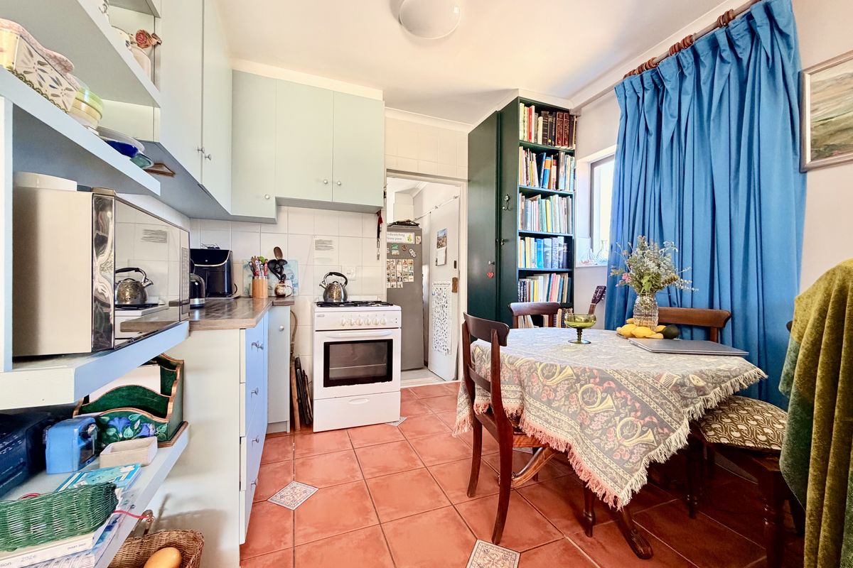 A functional kitchen featuring light-colored cabinetry, a gas stove with oven, and tiled flooring, with an integrated dining area.