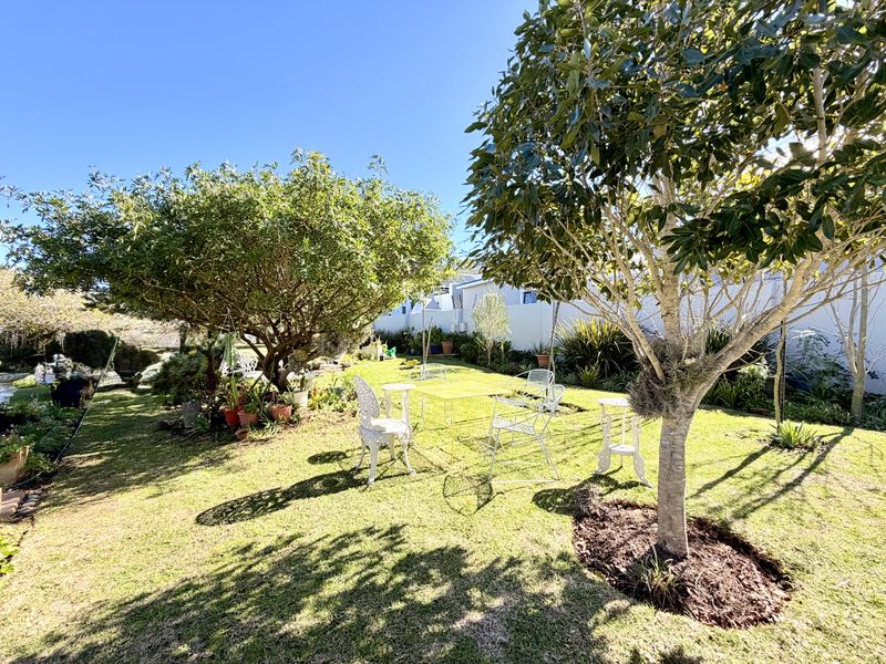A well-maintained private garden featuring mature trees, lush lawn, and a secure boundary wall, providing a peaceful outdoor space.