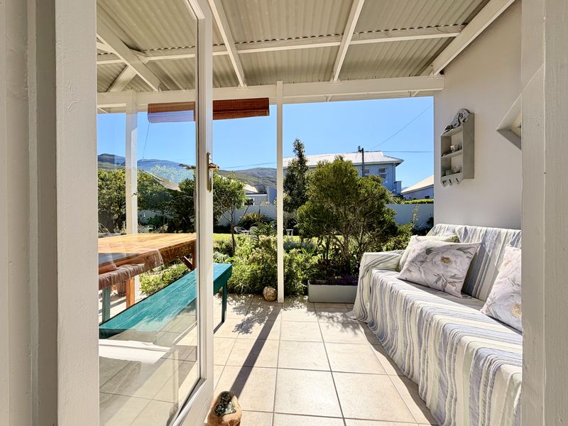 A covered patio area featuring tiled flooring and a corrugated roof, providing a seamless transition to the garden and outdoor space.