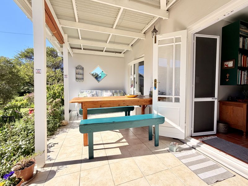 A covered outdoor patio featuring tiled flooring, timber support posts, and direct access to the interior through classic french doors.