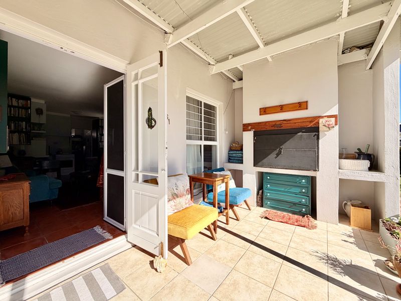 Covered patio area featuring tiled flooring, a built-in braai, and direct access to the interior living space through classic french doors.