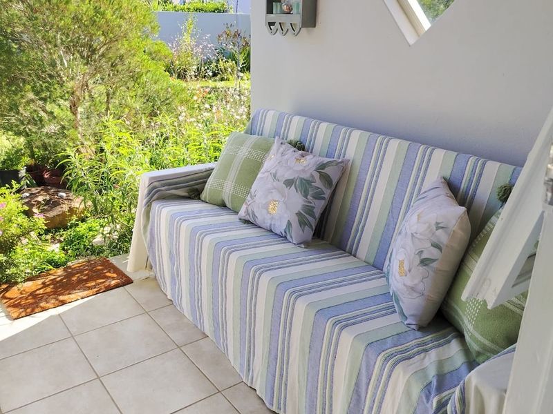 A covered patio area featuring tiled flooring and a unique diamond-shaped window, overlooking a lush garden space.