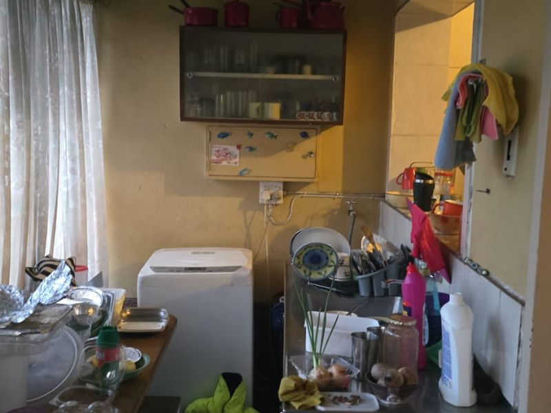 A compact scullery or utility area featuring a stainless steel sink, wall-mounted cabinetry, and a convenient pass-through window to the adjacent room.