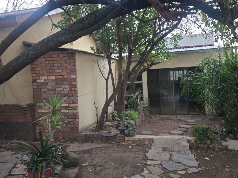 Rear exterior view of the property featuring a brick and plaster facade, sliding glass doors, and a stone pathway leading to the entrance.