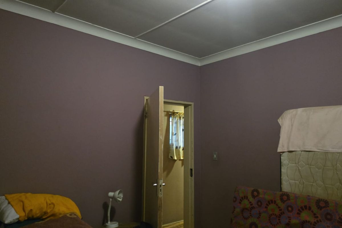 A bedroom featuring painted walls and coving, with an internal door leading to an adjacent space.