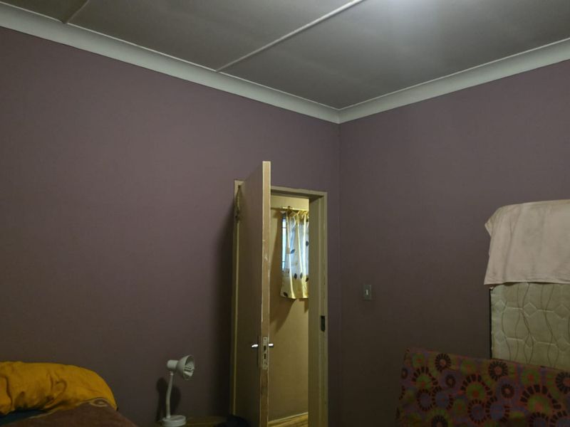 A bedroom featuring painted walls and coving, with an internal door leading to an adjacent space.