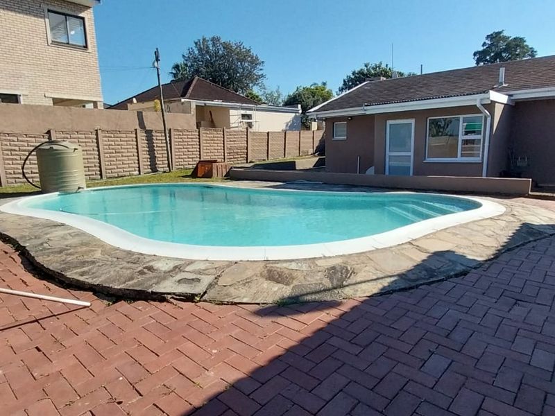 Outdoor pool area featuring a swimming pool with paved surround, boundary wall, and direct access to the main dwelling via sliding doors.