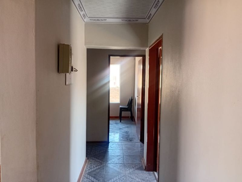 A functional hallway featuring tiled flooring and decorative ceiling cornicing, providing access to adjacent rooms within the property.