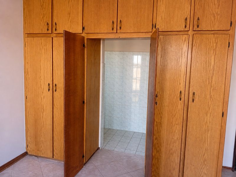 Bedroom featuring extensive built-in wooden cabinetry with overhead storage and an adjoining tiled alcove area.