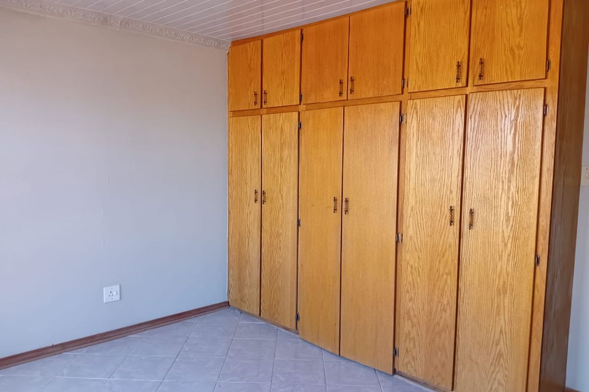 A bedroom featuring extensive built-in wooden cabinetry, tiled flooring, and a classic tongue and groove ceiling.
