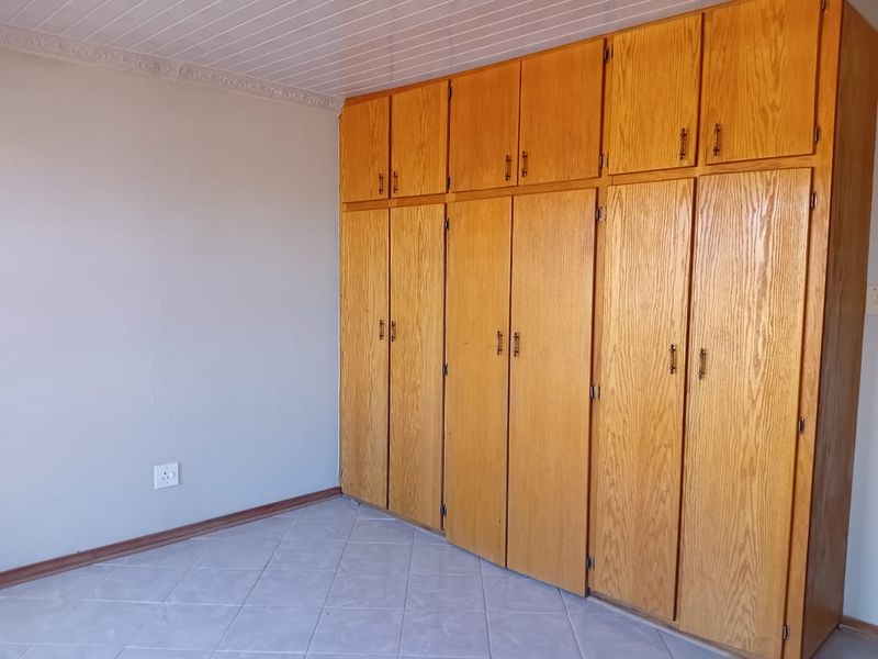 A bedroom featuring extensive built-in wooden cabinetry, tiled flooring, and a classic tongue and groove ceiling.