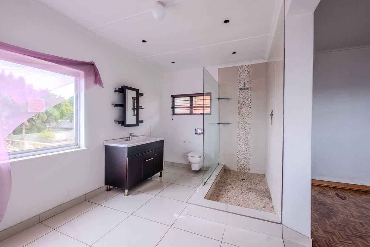 A functional bathroom featuring a vanity unit, a walk-in shower with a glass screen, and tiled flooring throughout.