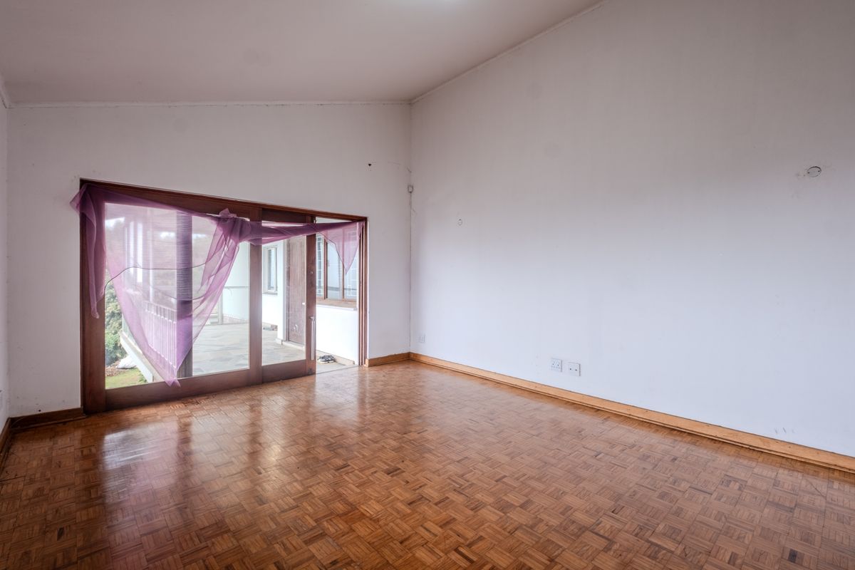 An empty living room featuring classic parquet flooring and a large sliding glass door providing access to an outdoor area.