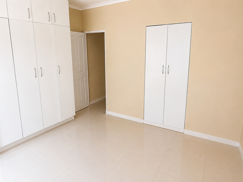A bright, empty bedroom featuring extensive built-in white cabinetry, neutral wall tones, and clean tiled flooring throughout.