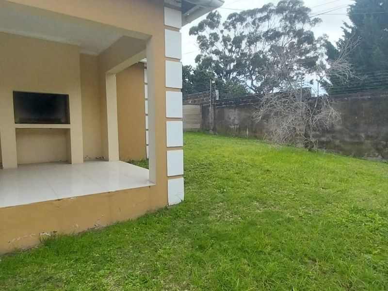 Covered patio featuring a built-in braai, leading out to a private garden area enclosed by a perimeter wall with electric fencing.