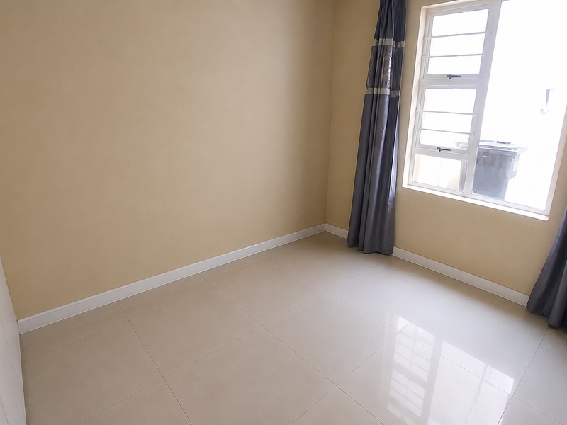 A clean, empty bedroom featuring neutral tiled flooring, a built-in wardrobe, and a window fitted with security bars.