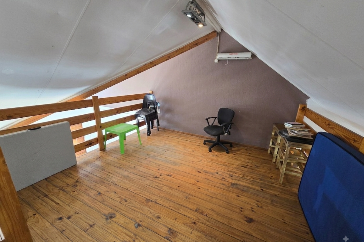 Loft-style bedroom featuring timber flooring, a wooden balustrade, and a split-system air conditioner under a pitched ceiling.