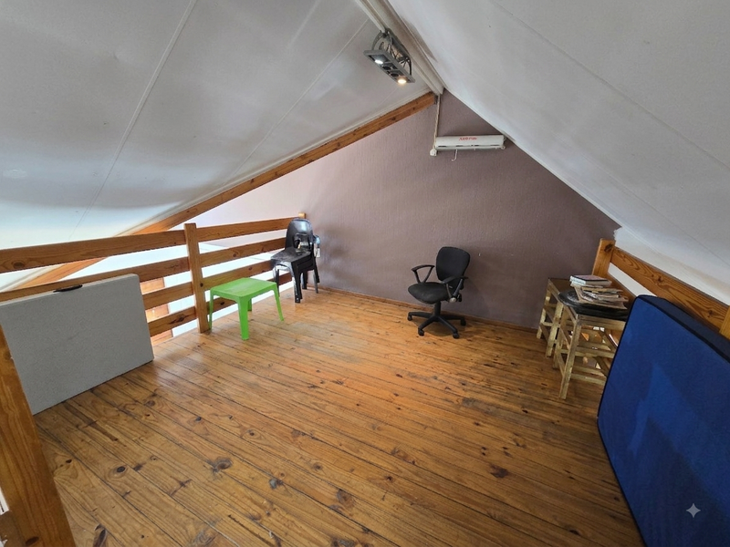 Loft-style bedroom featuring timber flooring, a wooden balustrade, and a split-system air conditioner under a pitched ceiling.