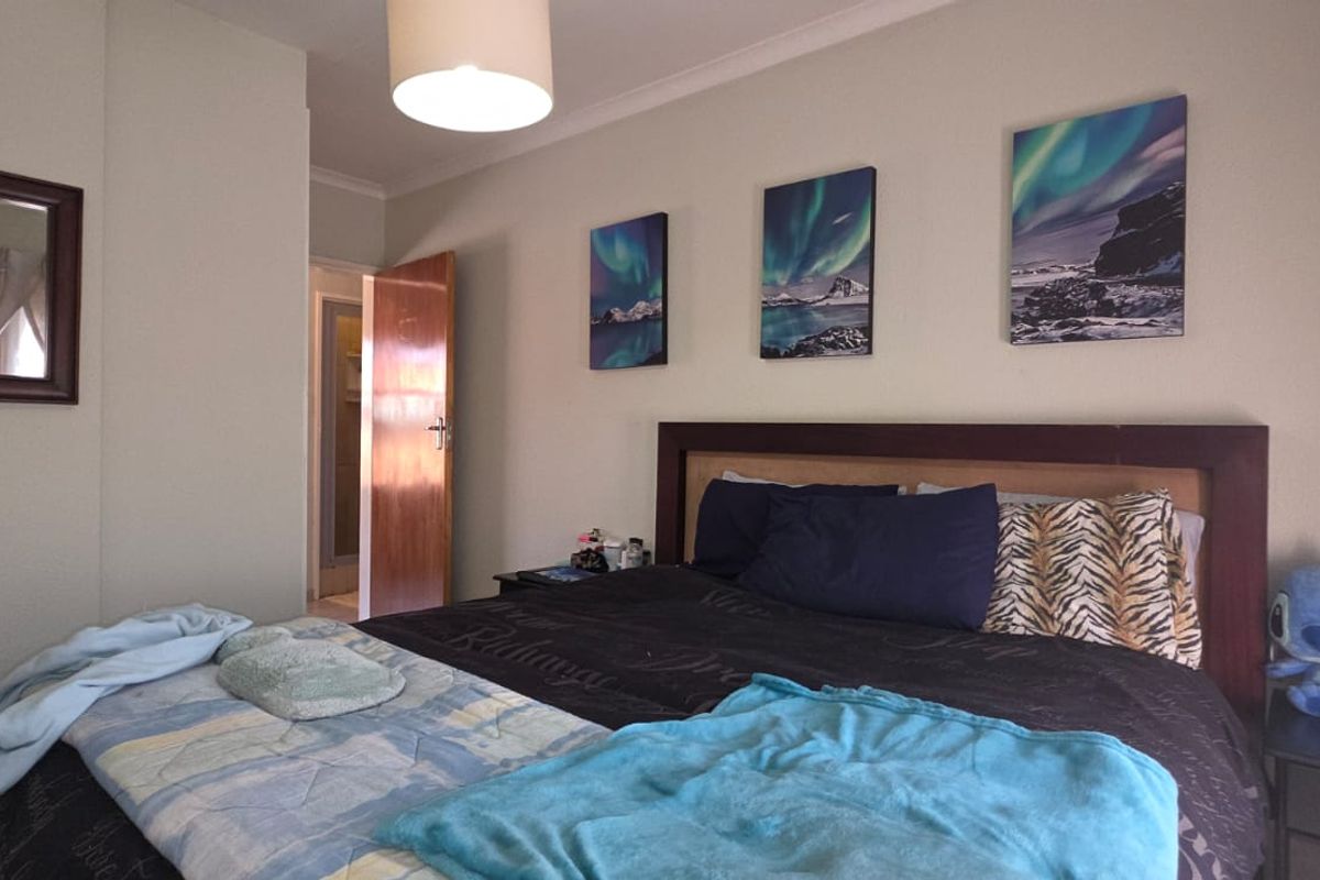 A standard bedroom featuring neutral wall finishes, cove cornicing, and a solid core door leading to an adjacent room.