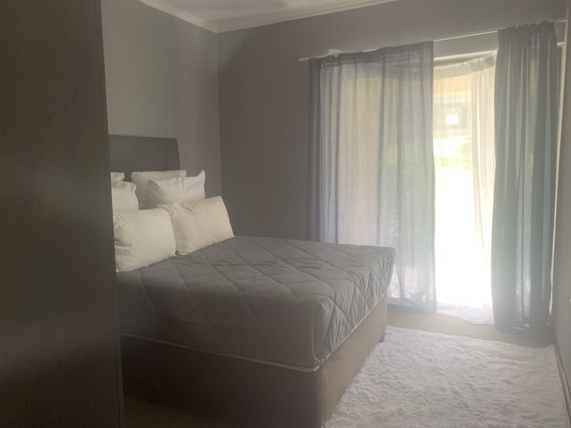 A bedroom featuring neutral grey walls and a sliding glass door providing access to the outdoors.