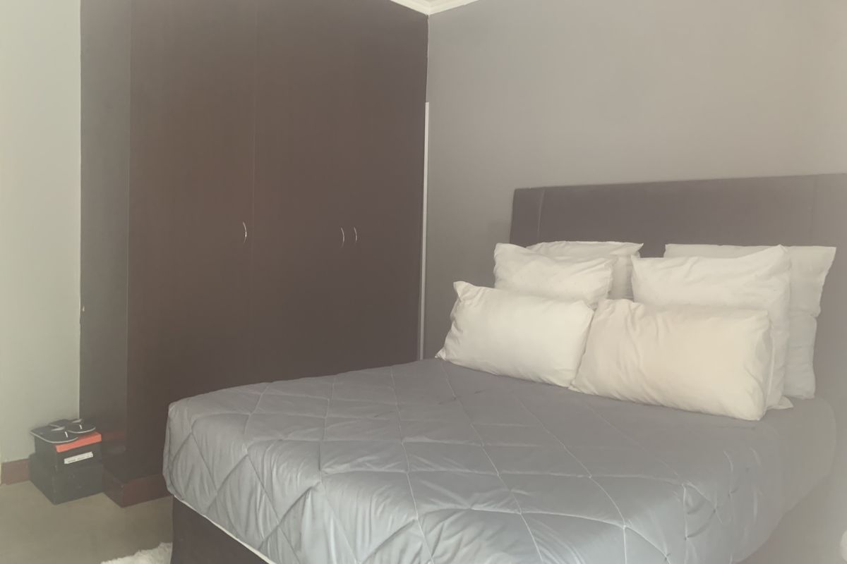 A bedroom featuring a dark wood built-in wardrobe and neutral wall finishes.